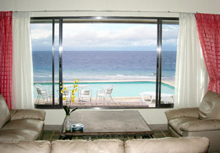 ホテルの一室より窓の外のプールと海を眺めるイメージ写真